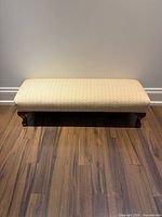 Front view of the yellow and gold upholstered fireplace bench showing the wooden legs and bench seat.