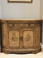 Front view of commode cabinet showing drawer and double doors with floral panels