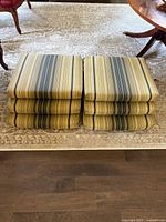 Six stacked outdoor cushions, striped beige/blue/green fabric