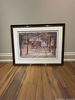 Framed winter night scene print by Trisha Romance against a plain background on wooden floor.