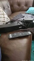 Soundbar, remote, power cord on couch
