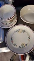 Stacked cereal bowls on luncheon plate next to dinner plate and serving bowl