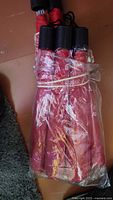 Bundle of six red umbrellas wrapped in plastic