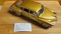 Gold 1:24 scale 1948 Tucker die-cast car on display with certificate