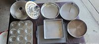 Group of metal bake pans including muffin tin, square pan, baking sheet, tube and Bundt pans, springform pans