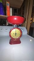 red analog food scale with bowl on appliance top