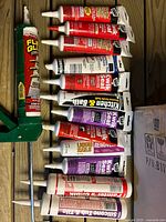 Multiple tubes of sealant and green metal caulk gun