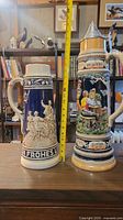 Both steins side by side showing relative size and decoration