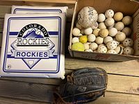 Overview of lot with two Rockies cushions, box of balls and glove