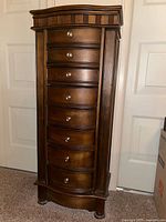Front view of tall solid wood jewelry armoire showing drawers and side panels