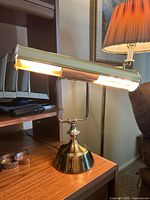 Brass adjustable table lamp lit with bulbs, side view