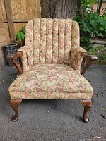 Front view of the 1940s floral patterned cushioned armchair showing tufted backrest, wooden armrests, and legs.