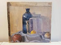 Front view of the oil on board still life painting showing bottles, candlestick, lemon, and pottery with edge wear