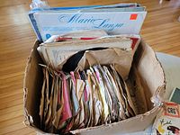 Photo showing a box filled with a dozen LP records including Mario Lanza and others, with visible wear on sleeves.