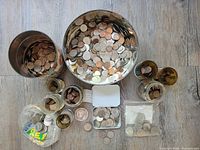 Overview of multiple tins, jars, bags containing various coins