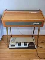 Frontalini organ closed view showing wood case with fabric speaker grill and legs