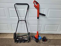 Yardworks push reel lawnmower next to Black & Decker electric weed whacker and accessories