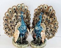 Front view of the pair of peacock spill vases showing detailed feather design and colors