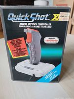 Front view of the Quick Shot XII Deluxe Joystick Controller box showing product name, features, and compatibility with Nintendo systems