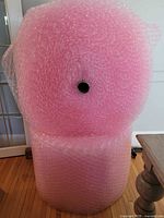 Two large rolls of pink bubble wrap stacked one on top of the other showing size and shape