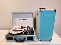 Front view of the Victrola turntable open showing the turntable platter, tonearm, and power cord next to a matching carrying case.