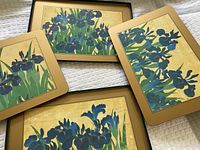 Four rectangular placemats with blue iris floral prints on a gold background with border.