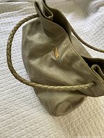 View of large supple pistachio leather shoulder bag with braided leather straps.