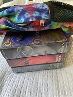 Folded books stacked with a tie-dye JanSport backpack placed beside them, showing book spines and part of backpack