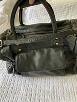 Top view of teal leather carry-on bag showing double handles and leather flap front pocket with brass zippers