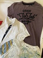 Photo of six folded women's casual tops and polo dress in various colors and prints including Superdry and Black Fleece.