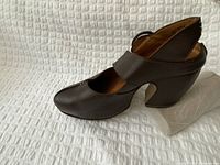 Brown leather heeled Mary Jane-style clog with metal buckle strap, square toe and block heel, photographed in profile.
