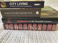 Four stacked books showing titles: City Living, 150 Best of the Best Apartment Ideas, Architecture in the Twentieth Century, The House Book.