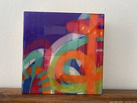 Front view of the wooden cube art piece displaying the colorful abstract design with a high gloss finish.