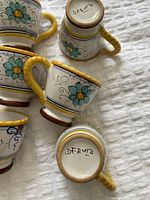 Close-up view of two espresso cups turned upside down revealing "DERUTA" markings on the bottom.