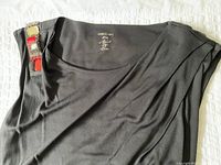 Top view of black Marc Cain dress showing jeweled decoration near shoulder and internal label with brand name and size small.