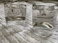 Two heavy clear glass candle holders side by side, showing the modern, thick glass design, recessed tops and concave bottoms