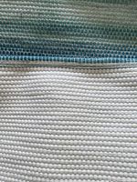 Close up photo of blue runner and white woven rag bedspread showing texture and weave.