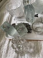 Photo showing multiple glass items on a tray including textured bowls, candle holders, and a star-shaped dish