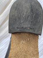 Close-up of See by Chloe brand embossed on the heel of one boot's sole showing moderate use wear