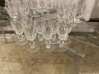 Full view of the stemware set arranged on a glass table showing various sizes and styles of glasses with vintage cut patterns