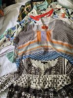 Full view of five women's patterned tops layered showing floral, stripes, and geometric patterns.