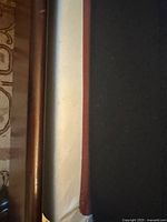 Close up of the brown frame edge of the box spring on a patterned carpet.