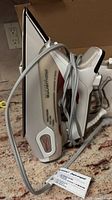 Side view of Rowenta clothes iron showing the body, handle, and cord coiled around it placed on a countertop.