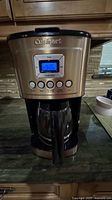 Front view of Cuisinart coffee machine on kitchen counter, showing control panel and glass carafe.
