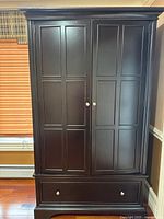 Front view of a dark wood dresser with closed double panel doors and two drawers at the bottom.