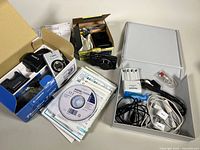 Lot contents showing Canon PowerShot S500 camera, boxed with charger, cases, cables, CD, manuals, and Fujifilm FinePix F770 EXR camera with accessories on table