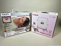 Photo of both original boxes: HoMedics kneading shiatsu massager and Canon Pixma mini 260 photo printer with branding visible