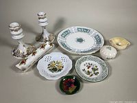 Angle view showing all items in the lot including candlesticks, plates, dishes, and creamers.
