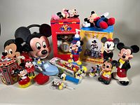 Full assortment of Disney Mickey Mouse toys and collectibles showing clocks, water globe, carrying case, figures, and other small items.