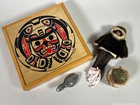 Photo showing all four items in the lot: soapstone bird carving, porcupine quill box, fur parka doll, and wood box with mask and salmon art by Clarence A Wells.